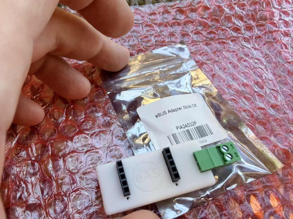 The eBUS Adapter Stick C6 out of its antistatic bag, with the pluggable green two-pin terminal block alongside